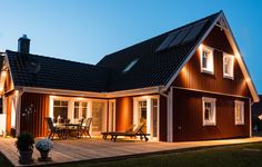 a house that is lit up at night with lights on the roof and patio area