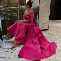 a woman in a pink dress sitting on a chair