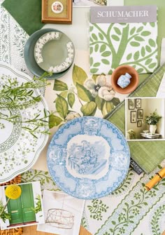 a table topped with plates and pictures next to green wallpaper covered in leaves, flowers and other things