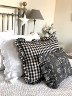 the pillows are piled on top of each other in front of a bed with white linens