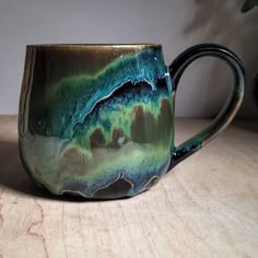 a green and blue mug sitting on top of a wooden table