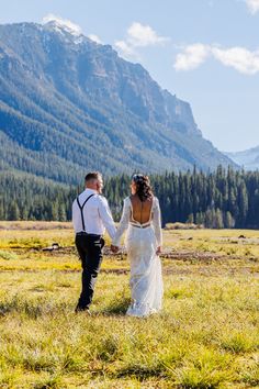 a bride and groom holding hands in the mountains