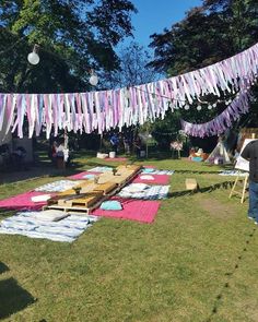 an outdoor party with picnic tables and blankets on the grass