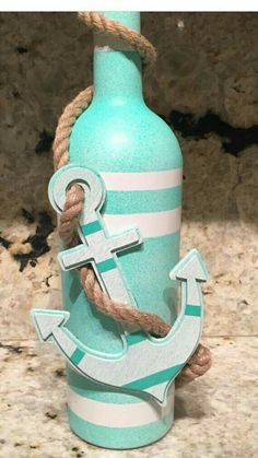 a bottle with an anchor and rope tied to it, sitting on a counter top