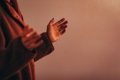 a woman is holding her hands out in front of the camera while wearing a brown coat