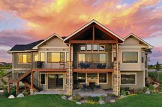 a large house sitting on top of a lush green field under a colorful sky with clouds