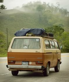 an old van with luggage on top driving down the road