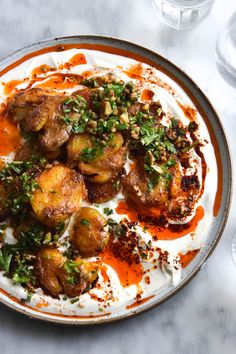 a white plate topped with potatoes covered in sauce and garnished with parsley