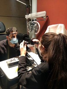 a man and woman are looking at something in front of a camera set up on a table