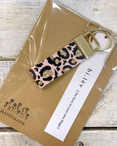 a pink and black leopard print keychain sitting on top of a brown envelope