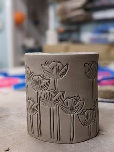 a clay vase sitting on top of a table next to other pottery items in the background