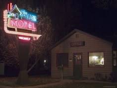 a motel sign lit up at night with lights on it's front and side