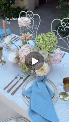 the table is set with silverware, flowers and blue napkins for an elegant dinner