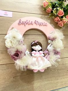 a pink and white wreath with a teddy bear on it