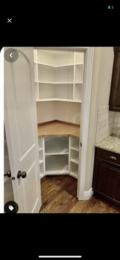 an image of a kitchen with wooden floors and white cupboards in arabic writing on the bottom right corner