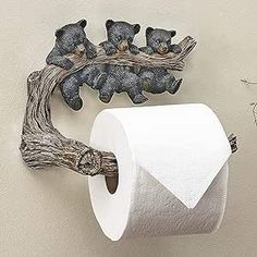 two teddy bears are sitting on the branch of a tree next to a roll of toilet paper