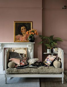 a living room with pink walls and a white couch in front of a painting on the wall