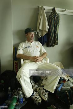 a man sitting in a chair next to baseball equipment