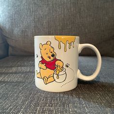 a winnie the pooh mug sitting on top of a couch with dripping yellow paint