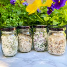 four jars filled with different types of herbs