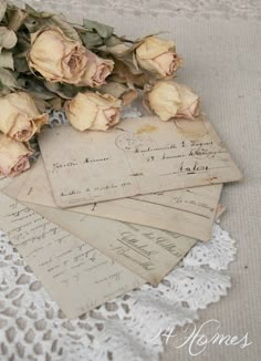 some old papers and flowers on a lace doily are laying on top of each other