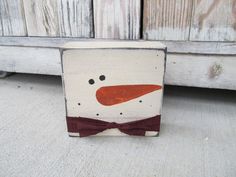 a wooden block with a snowman painted on it's face and bow tie