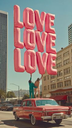 two people on top of an old car with the word love spelled in large letters