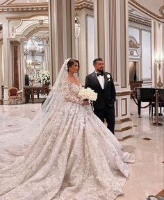 a man and woman in formal wear standing next to each other wearing wedding gowns