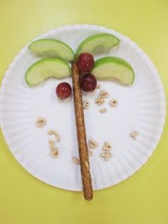 a paper plate with fruit on it and a stick made to look like a palm tree