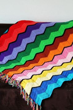 a multicolored crocheted afghan sits on a couch