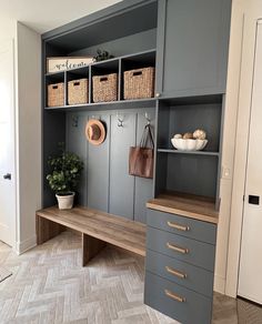 a room with gray cabinets and baskets on the shelves next to a wooden counter top