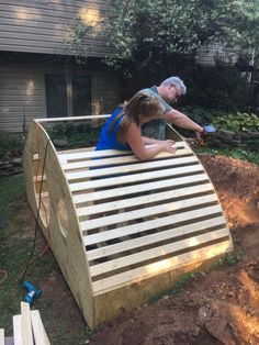 two people working on a wooden structure in the yard