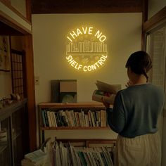 a woman reading a book in front of a neon sign that reads i have no self control