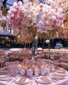 the centerpieces are filled with pink and white flowers, gold rimmed candles and place settings