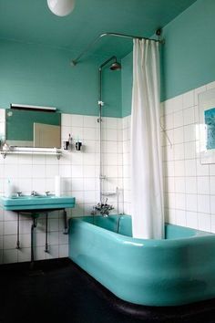 a bathtub and sink in a bathroom with white tiles on the walls, black flooring and blue accents