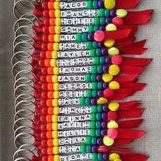 many different colored pencils are lined up on a white surface with name tags attached to them