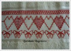 a close up of a red and white cloth with hearts on the side, in an embroidered pattern