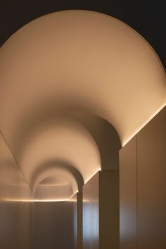 an empty hallway with white walls and lights on the ceiling is lit up by daylight