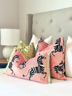 two pink pillows with zebras on them sitting on a bed