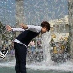 a young man riding a skateboard in front of a fountain with water spraying from it