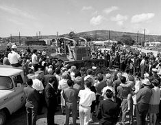 a crowd of people standing next to each other near an old truck and tractor trailer