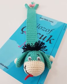 there is a crocheted stuffed animal that looks like a person hanging from a book