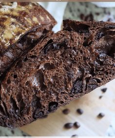 two pieces of chocolate bread sitting on top of a cutting board next to coffee beans