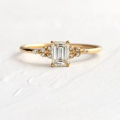 a gold ring with an emerald cut diamond surrounded by small diamonds