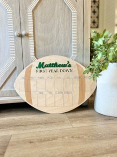 a wooden football shaped calendar sitting next to a potted plant