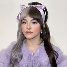 a woman with long hair wearing a purple fur coat and pink bow around her head