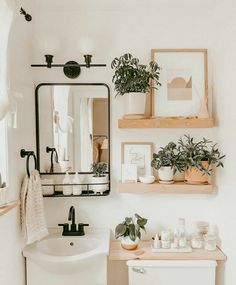 the bathroom is decorated in white and has plants on shelves above the sink, along with potted plants