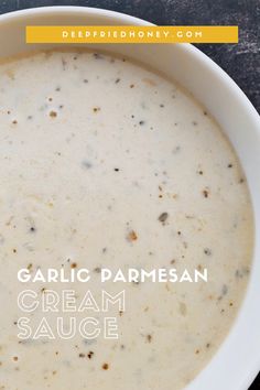 a white bowl filled with cream sauce on top of a black table next to a spoon