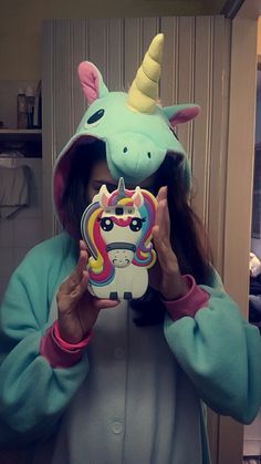 a woman in a unicorn costume holding up a mirror to her face with the image of a unicorn on it