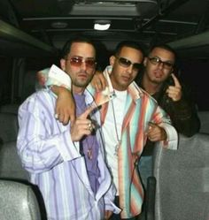 three men standing next to each other in the back of a bus with their arms around one another